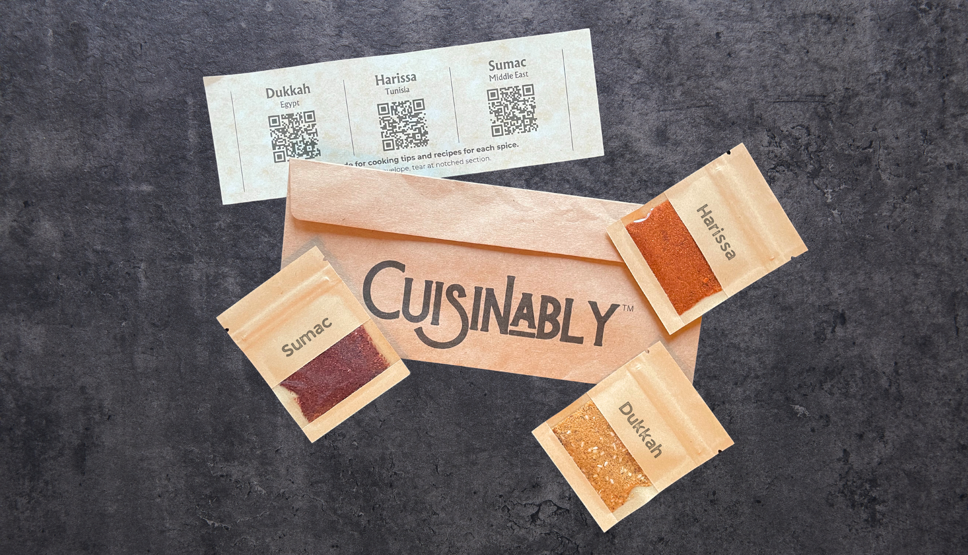 Envelope with Cuisinably logo, three pouches of spices, and a paper slip with QR codes.